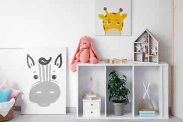 Picture and shelving unit with toys near white wall in children's room