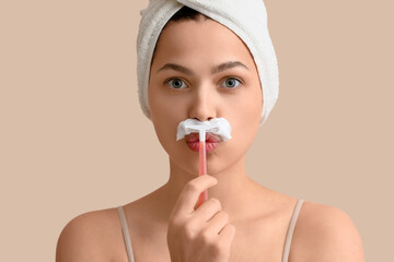 Beautiful young thoughtful woman with razor and shaving foam on beige background. Depilation concept