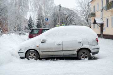 Side view of snow covered car parked near the houses