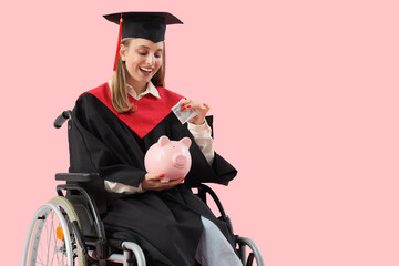 Female graduate in wheelchair putting money into piggy bank on pink background