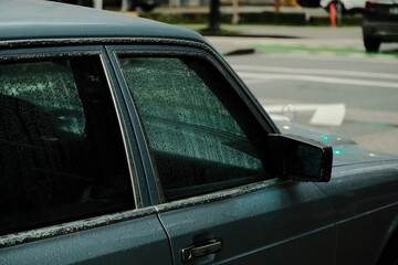 Close-up of a vintage luxury car on a rainy day.