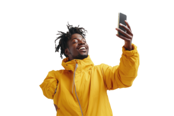 Young man in a yellow jacket smiling while taking a selfie on a smartphone against a plain white background
