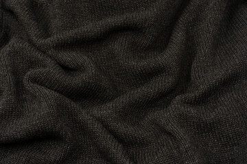 Dark grey sweater texture as a background. Knitted pattern.