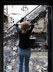 A devastated woman looks at the interior of a house destroyed by a house fire.