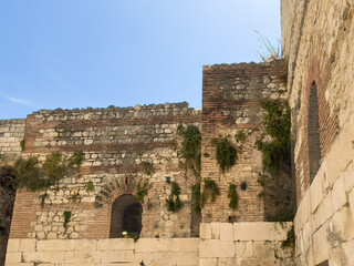 Split, Croatia - July 1, 2024: Historic Diocletian Cellars and Palace. Upper levels with plants growing in cracks of the walls under blue sky