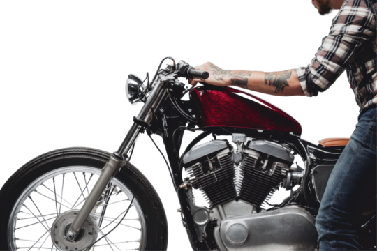 Man in plaid shirt working on a custom motorcycle in a studio with white background showcasing detailed craftsmanship and mechanical precision