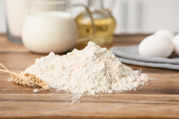 Heap of flour with ears of wheat for preparing dough on kitchen counter