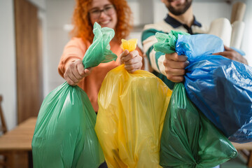 Portrait of man and woman with plastic green, yellow and blue bags