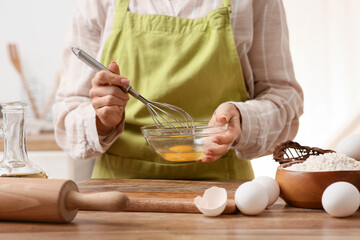 Woman preparing dough with eggs and flour on kitchen counter