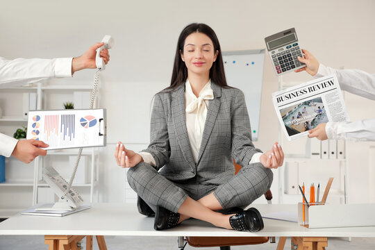 Young businesswoman with newspaper, calculator, telephone and charts meditating on table in modern office