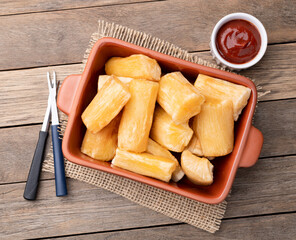 Traditional brazilian fried manioc in a plate with ketchup, pepper and beer over wooden table