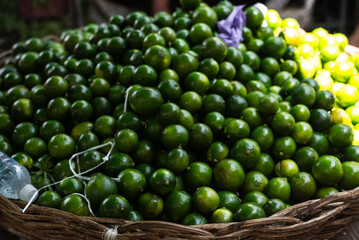 Green lemon for sale at a stand. Oval citrus fruit, dark green to yellow in color, with smooth or wrinkled skin, rich in vitamin C.