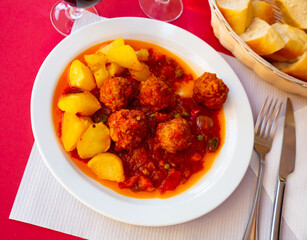 Appetizing albondigas, traditional Spanish meatballs with vegetable salsa and potato garnish