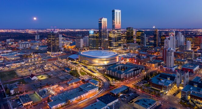 Nighttime aerial view of downtown Edmonton, Alberta, Canada. Modern skyscrapers and the Rogers Place arena are illuminated. City lights create a vibrant scene, Edmonton, Alberta, Canada