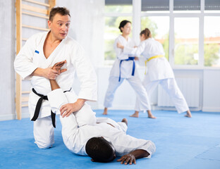 Multinational athletes paired up woman in sparring practice elbow strike with wrist grip on...