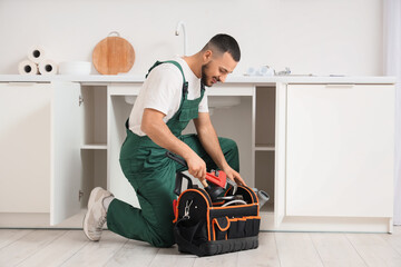 Male plumber with tool bag near sink in kitchen