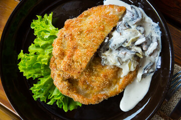 Delicious dinner pork schnitzel served with creamy mushroom sauce and greens