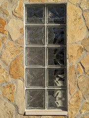 Textured glass grid square tile blocks, ochre natural stone and concrete facade wall, transparent...