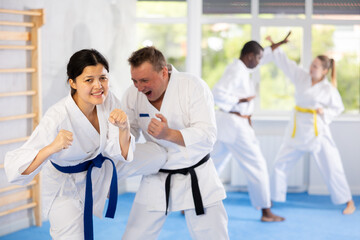 Active middle-aged woman attendee of karate classes practicing fighting techniques during workout session