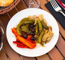On white background there is plate with beautifully laid baked eggplant, onion, red bell pepper.