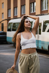 Woman enjoying a sunny day while posing elegantly in casual wear near a parked bus
