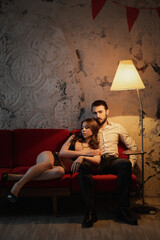 Intimate moment between a couple on a cozy red sofa in a softly lit room