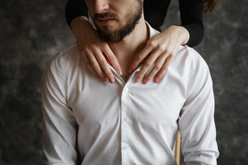 A girl stands behind a guy and hugs his neck, close-up of hands