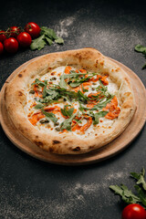 Gourmet pizza with smoked salmon, arugula, and capers on a wooden board for a delicious meal