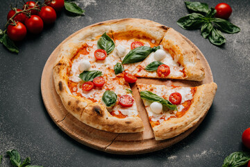 Freshly sliced Margherita pizza with basil, mozzarella, and cherry tomatoes on a rustic plate