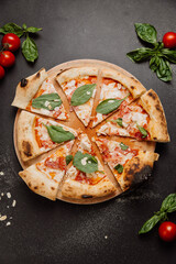 Freshly baked pizza slices with spinach, almonds, and tomatoes on a wooden board