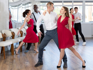 Energy man and girl are dancing tango in couple during lesson at studio. Leisure activities and...