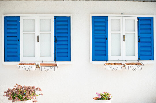 Blue and White Shuttered Windows with Flower Pots