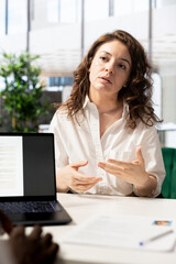 HR specialist using laptop to reviewing candidate CV, asking questions about qualifications. Person...