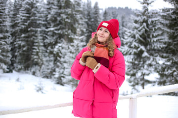 Woman tourist in a snowy forest in the mountains. Portrait of young happy smiling woman. Cozy hygge travel holidays retreat destination. Traveling in Ukraine Carpathians mountains