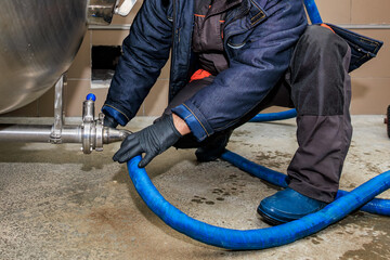 Industrial worker handling blue hose in factory setting