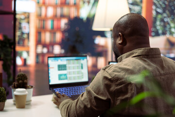 Entrepreneur reviewing statistics data on a laptop remotely from his house, makes a briefing...