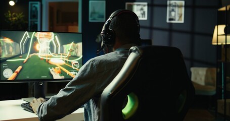Joyous gamer with headphones on having fun in gaming room, playing videogames on computer. Close up...