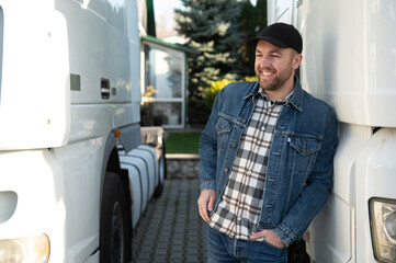 Happy confident male driver standing in front on his truck