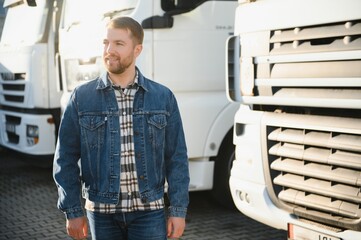 Transportation concept. Logistics. A handsome truck driver is standing near the cab before the trip