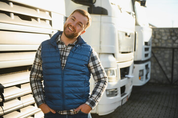 Transportation concept. Logistics. A handsome truck driver is standing near the cab before the trip