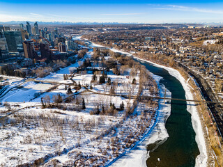 City skyline view overlooking Princess Island Park with ice skaters during winter with distant neighborhoods.