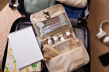 Open suitcase packed with clothing, toiletries, and travel essentials ready for a trip. Close-up.