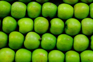 Close-up view of fresh green sour apples sold at the grocery store. Summer fruits. Organic farming. Vegetable and fruit prices. Vegetarian diet.
