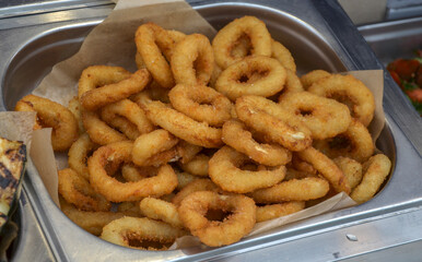 Golden-brown calamari rings prepared with a crispy coating, served hot in a buffet setting, perfect for seafood lovers and culinary enthusiasts
