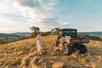 Man and woman chatting on hilltop with off-road farm buggy