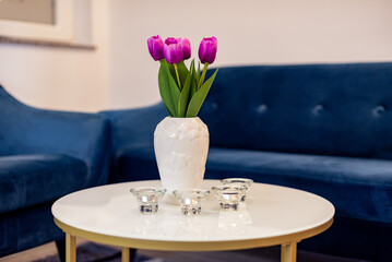 Vibrant purple tulips in a white ceramic vase on a modern round coffee table
