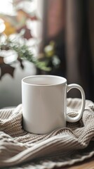 Fototapeta premium Cozy White Mug on Soft Knit Blanket with Natural Background