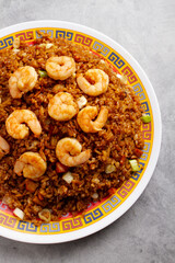Chinese fried rice with shrimp, served on a decorative Chinese plate, set against the backdrop of a polished marble surface.