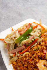 Shop suey, with fried rice and shrimp on a white plate on a marble background
