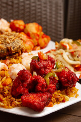Chinese food dishes of sour chicken, rice, shrimp and fried chicken on brown restaurant  table